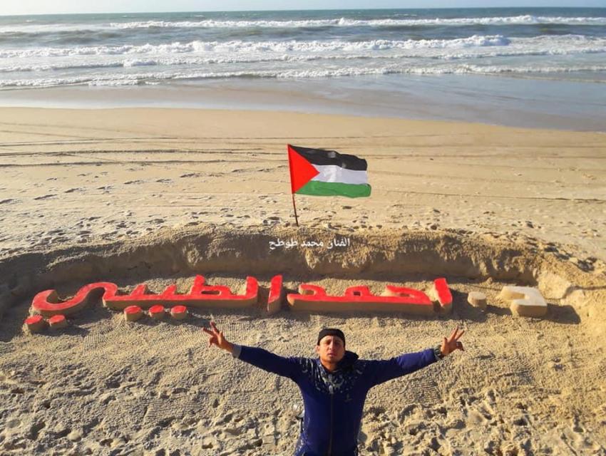 فنان فلسطيني ينحت اسم الطيبي برمل بحر غزة